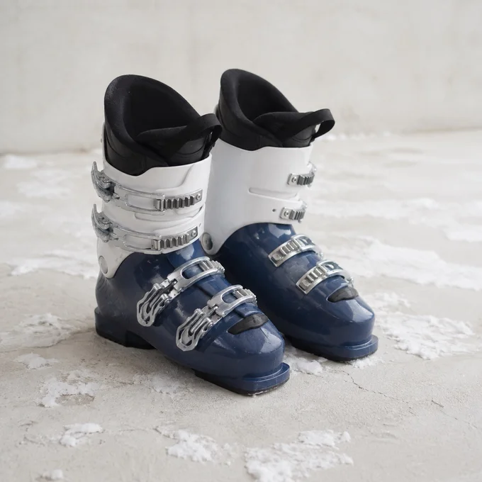 A pair of navy and white ski boots on a snowy surface